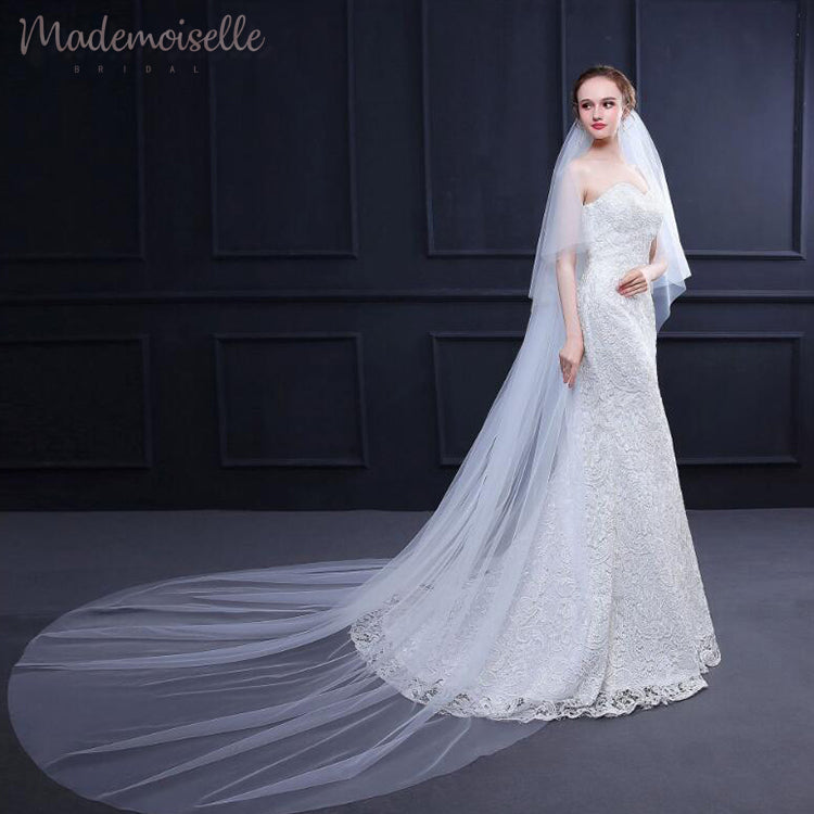 A beautiful bride dons a long veil with exquisite white lace trim, enhancing her bridal elegance and charm.